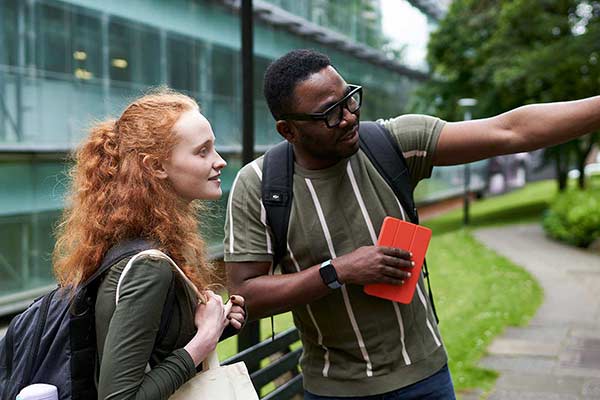 Two students in University gardens. One pointing out something to the other.